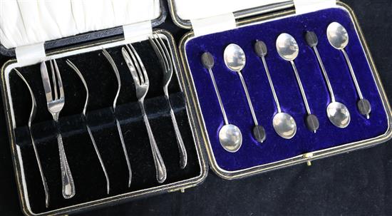 Two cased sets- six silver cake forks and six silver bean end coffee spoons.